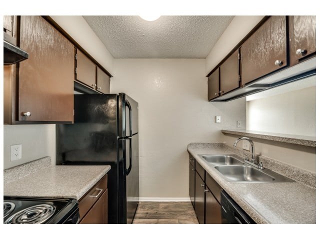 A kitchen with black appliances and brown cabinets.