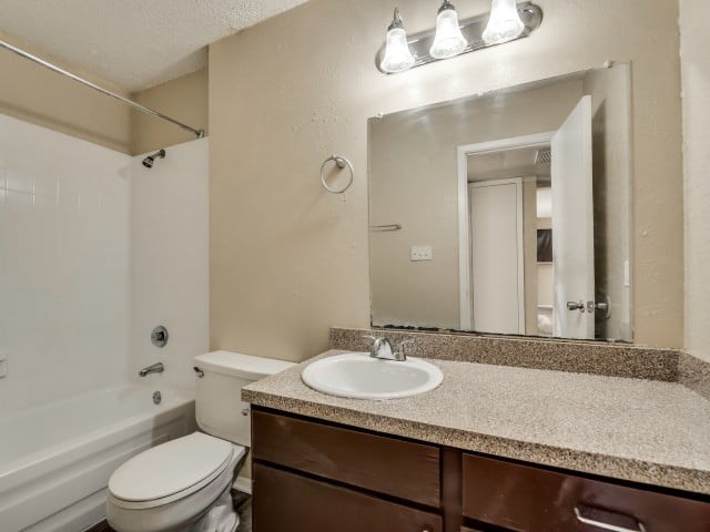 A bathroom with a toilet, sink, and mirror.