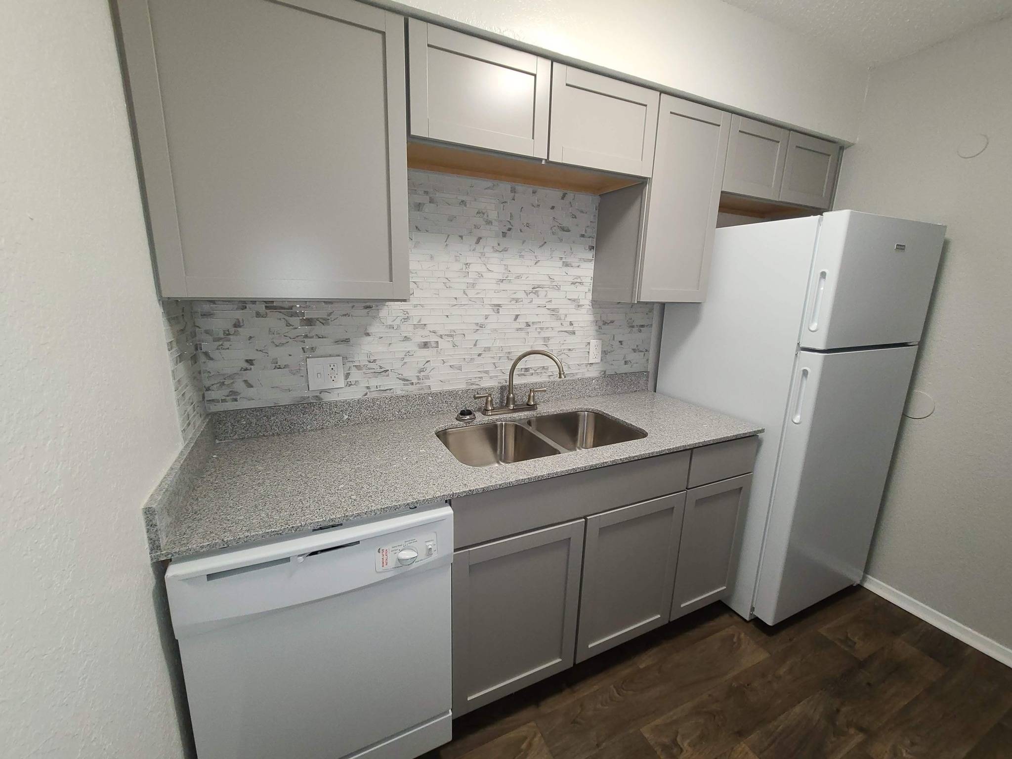 A kitchen with a white fridge, dishwasher and sink.
