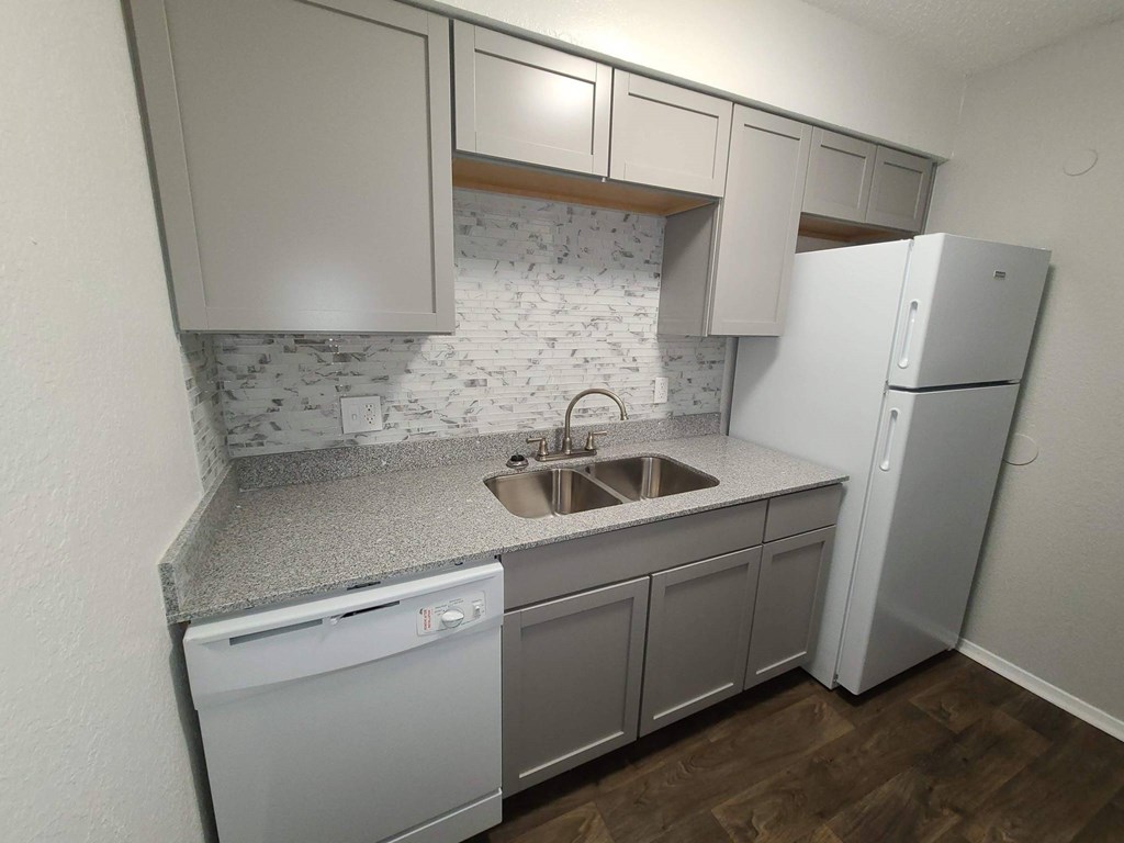 A kitchen with a white fridge, dishwasher and sink.
