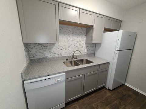 A kitchen with a white fridge, dishwasher and sink.