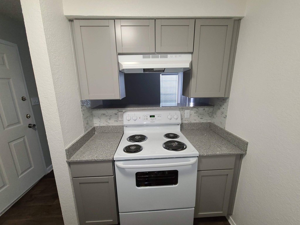A kitchen with a white stove top oven and a white dishwasher.