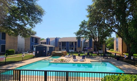 A swimming pool surrounded by a black fence and trees.