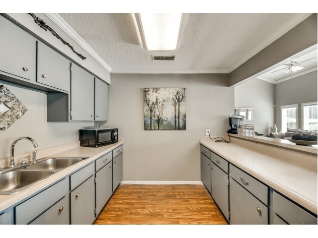 A kitchen with a sink, microwave, and cabinets.