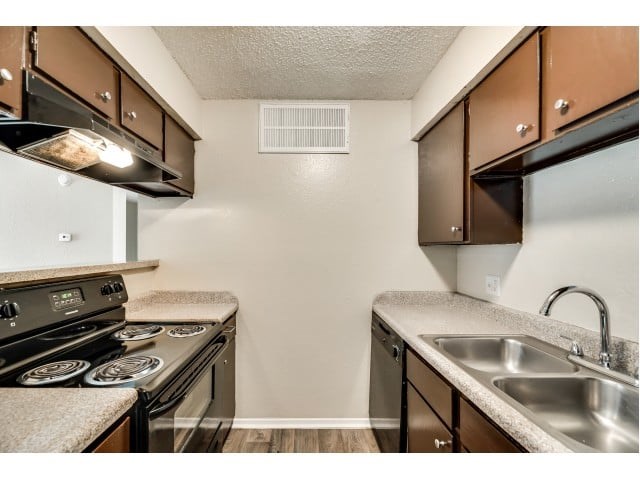 A kitchen with a stove, sink, and cabinets.