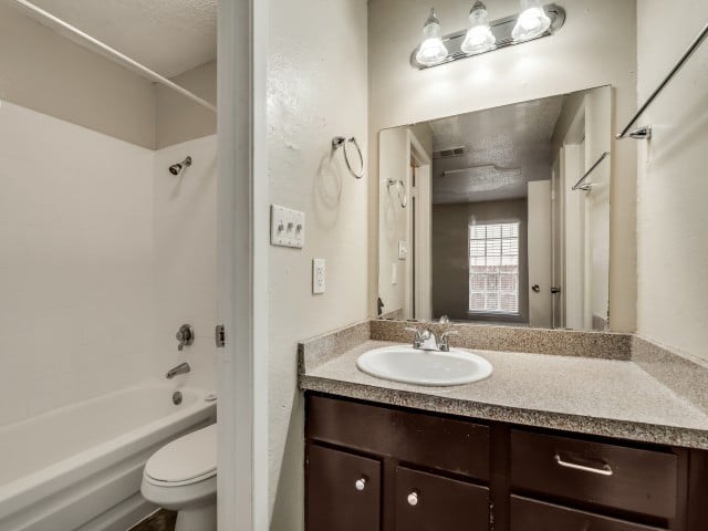 A bathroom with a sink, toilet, and a mirror.