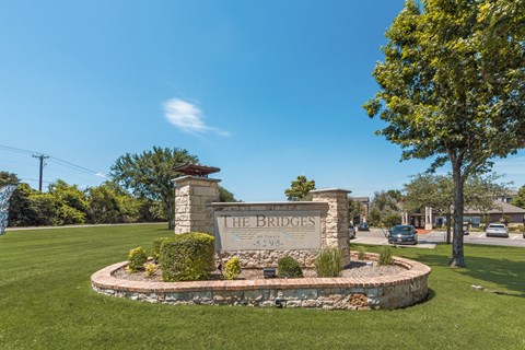 A sign that says "The Bridges" stands in a grassy area.