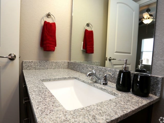 A bathroom with a granite counter top and a white sink.
