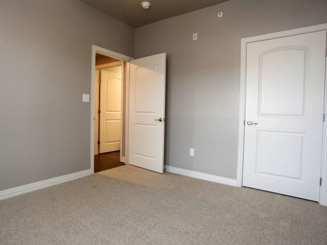 A room with two white doors, one open, and carpeted flooring.