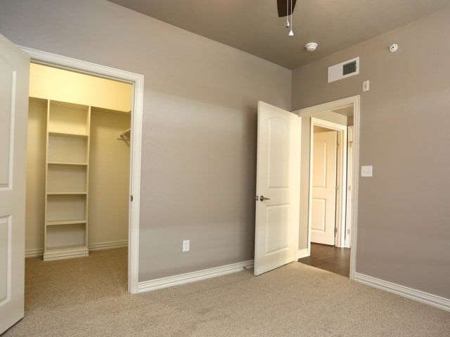 A room with a white door and a carpeted floor.