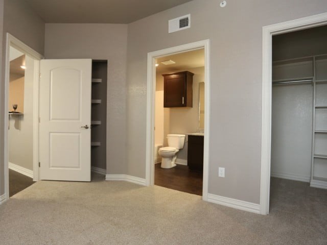 A white door is open to a bathroom with a toilet and a cabinet.
