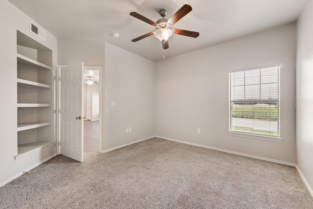 A room with a ceiling fan and a window with blinds.