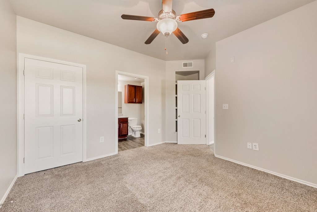 A room with a ceiling fan and carpeted floor.