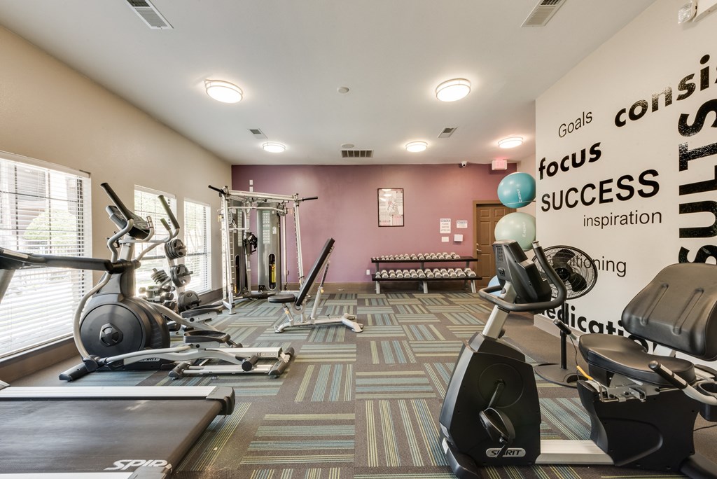 A gym with a variety of equipment including treadmills, weights, and exercise machines.