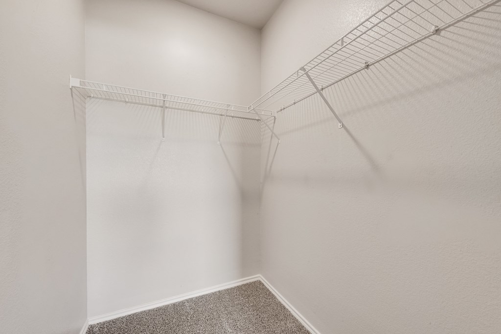 Empty white room with a wire shelf and carpeted floor.