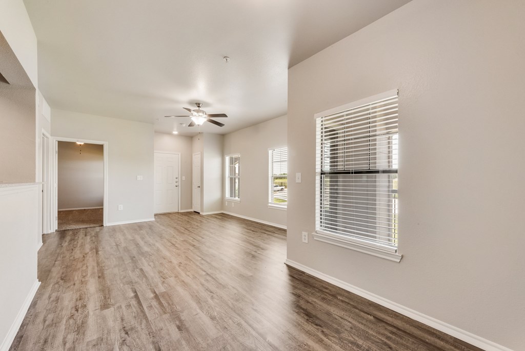 A spacious room with wooden flooring and a ceiling fan.