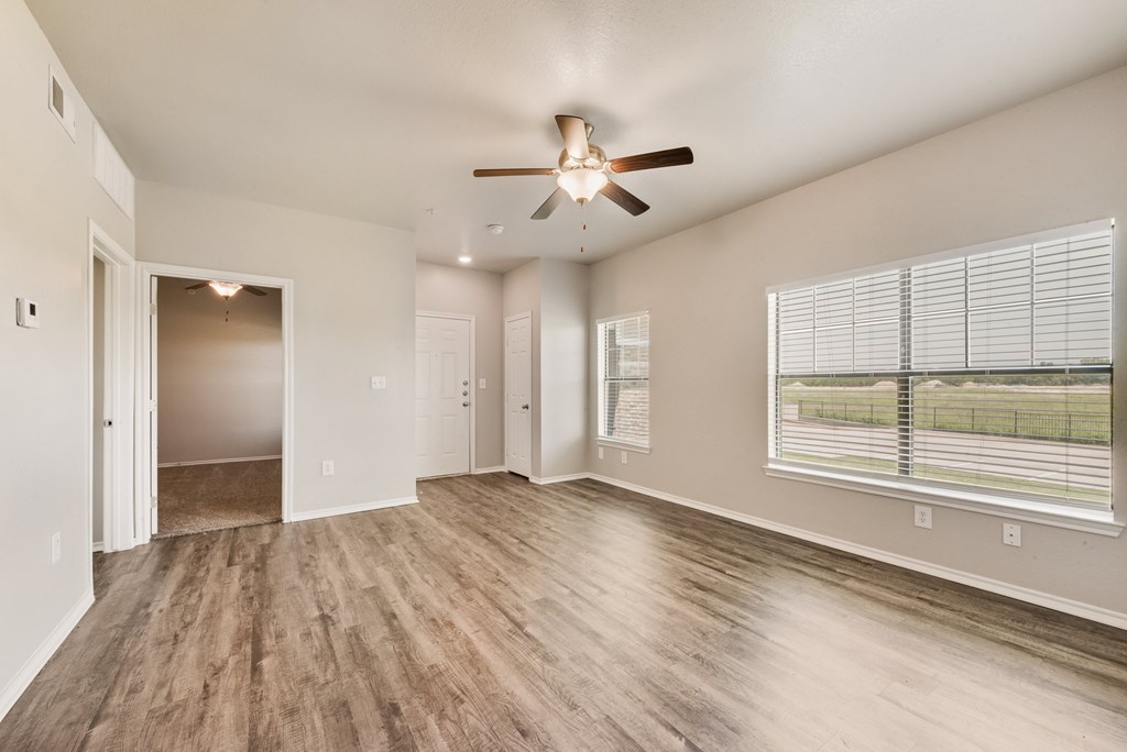A room with a ceiling fan and a window with blinds.