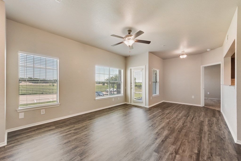 A room with a ceiling fan and wooden flooring.