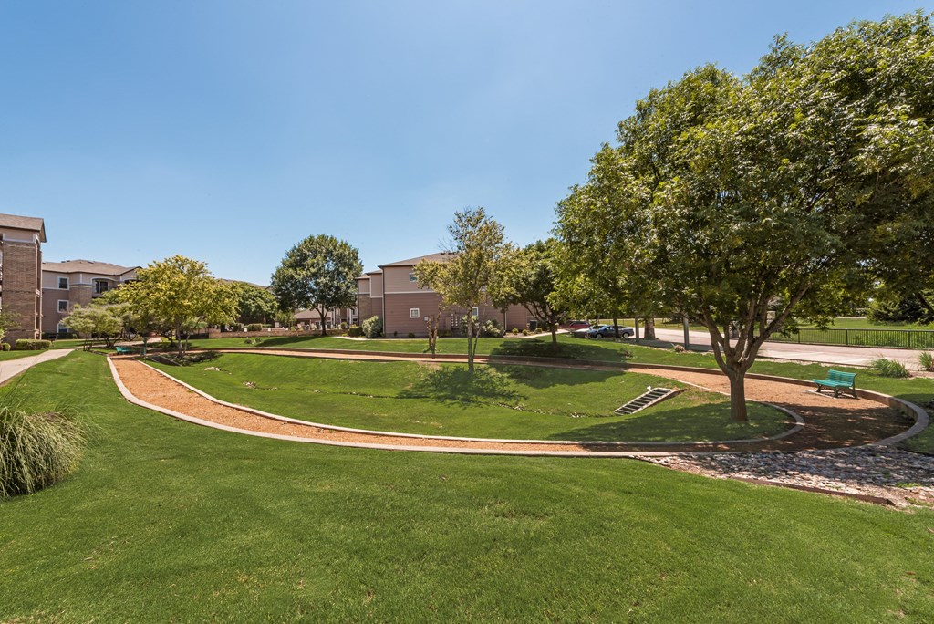 A tree in a grassy area with a building in the background.