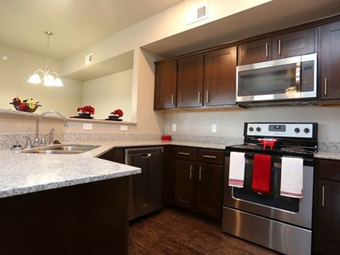 A kitchen with dark brown cabinets and a stainless steel oven.