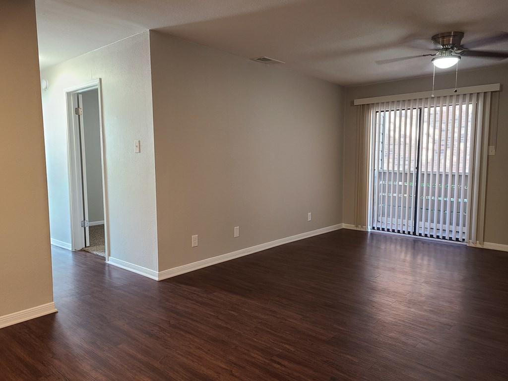 Empty room with wooden floors and a ceiling fan.