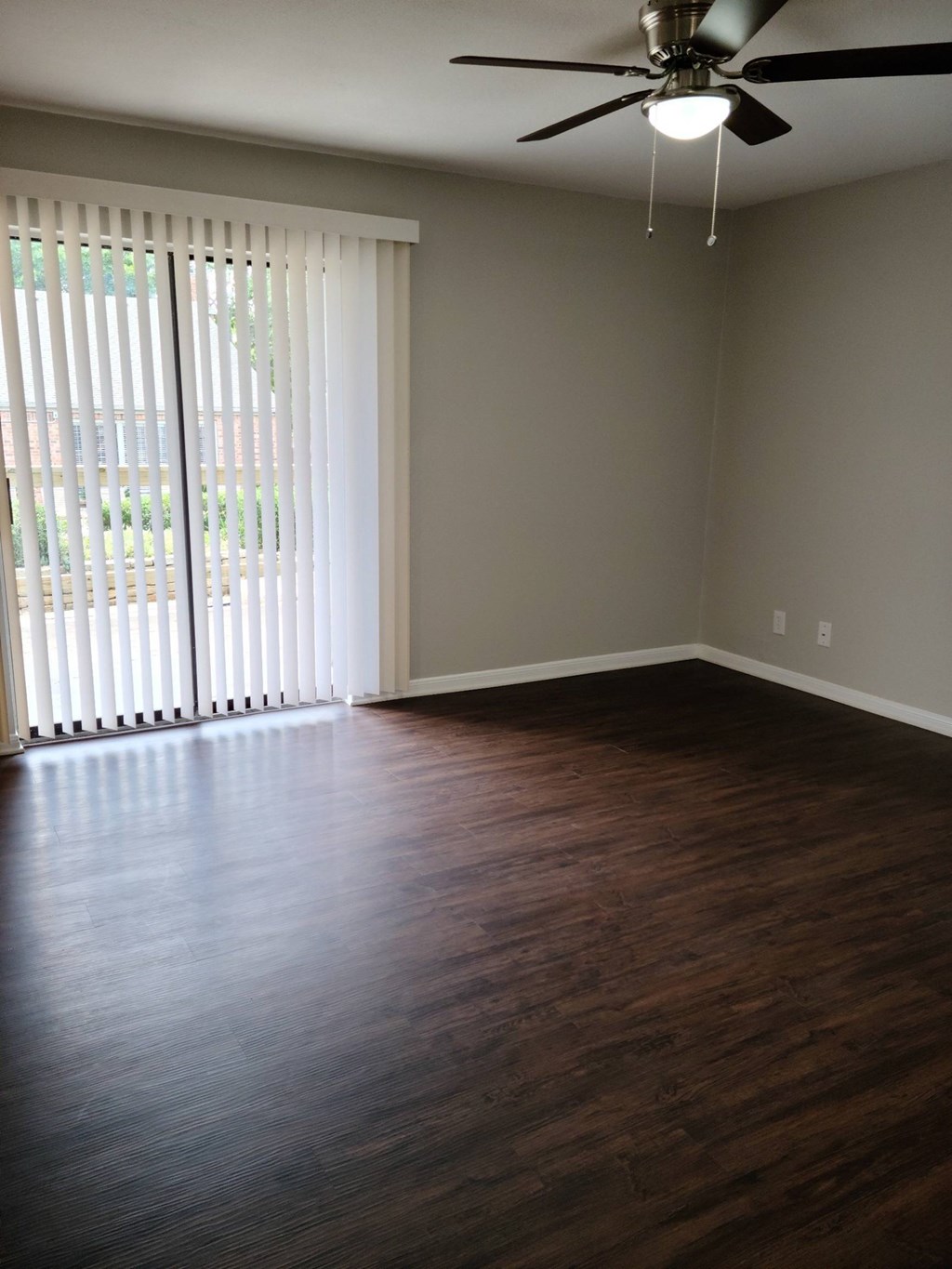 A room with a ceiling fan and wooden flooring.