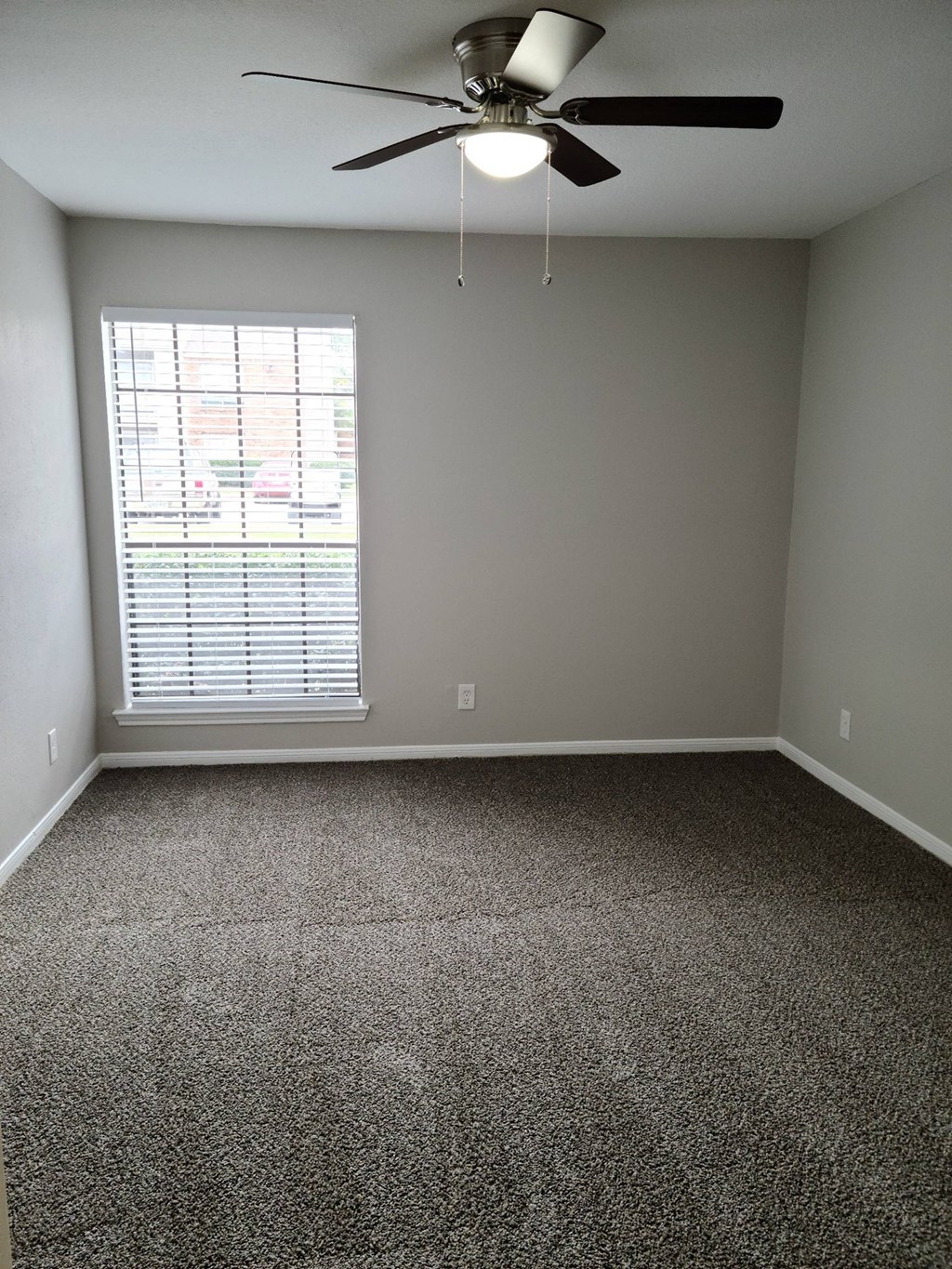 A room with a ceiling fan and a window with blinds.