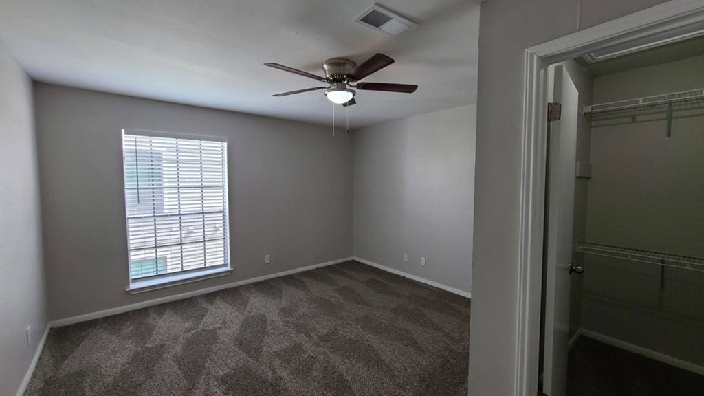A room with a ceiling fan and a window with blinds.
