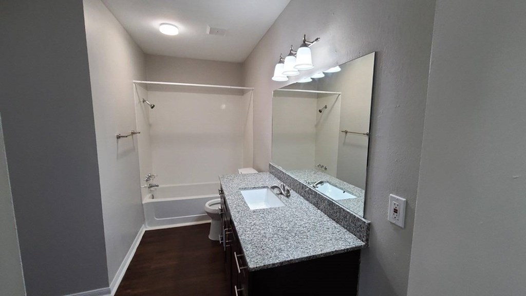 A bathroom with a sink, mirror, and bathtub.