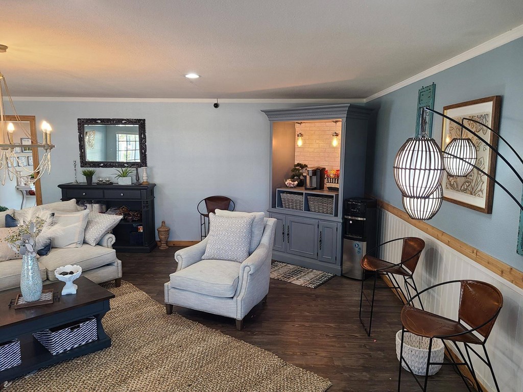 A living room with a grey sofa, a white armchair, a coffee table, and a TV.