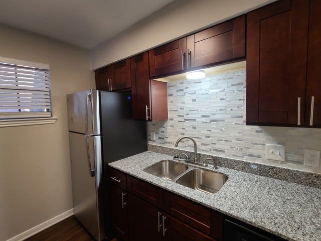 A kitchen with a black refrigerator and brown cabinets.