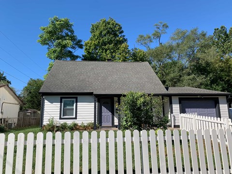 A house with a grey roof and a white picket fence.