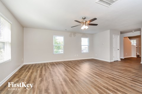 A spacious room with wooden flooring and a ceiling fan.