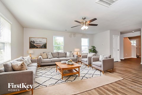A spacious living room with a large grey sofa, a wooden coffee table, and a painting on the wall.