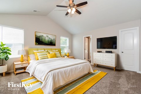 A bedroom with a bed, dresser, and a ceiling fan.