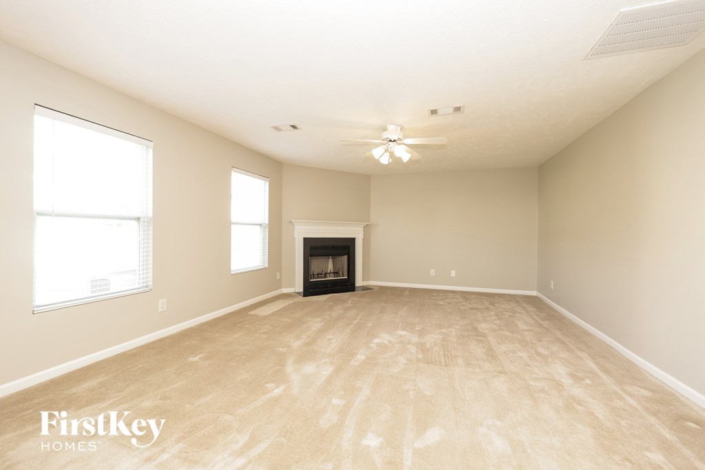 A spacious room with a fireplace and a ceiling fan.