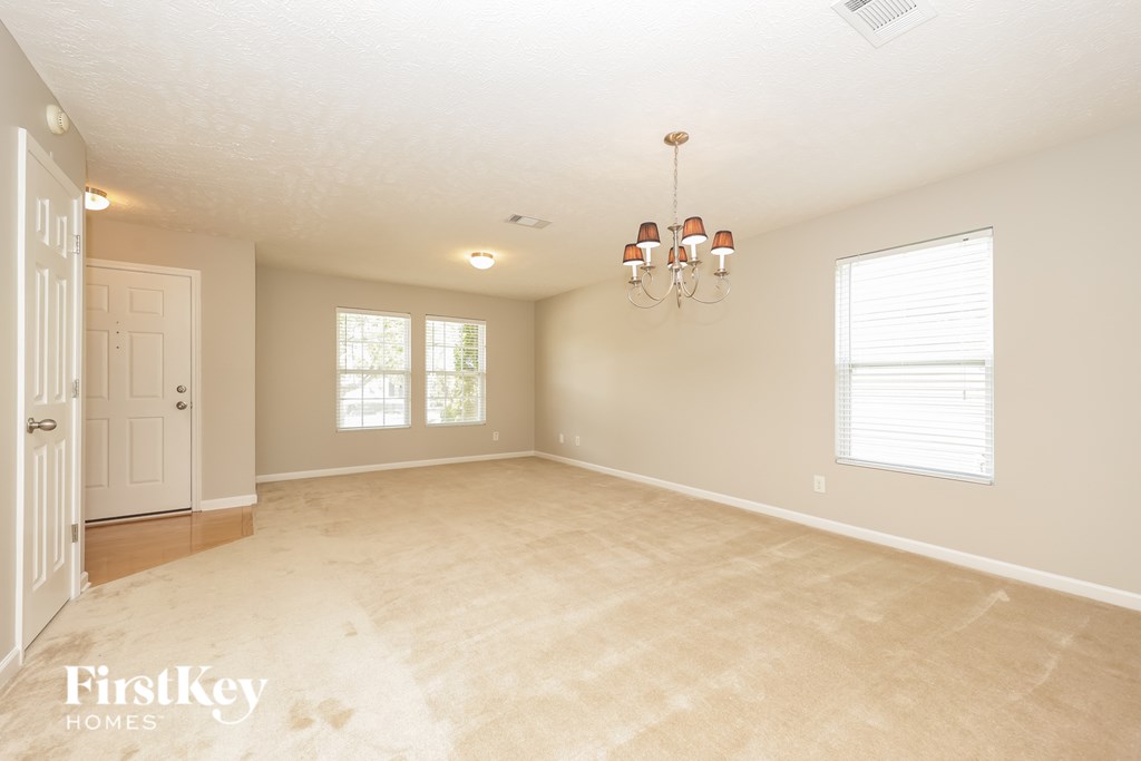 A spacious room with a chandelier and a door on the left.