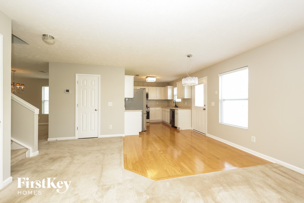 A spacious living room with a kitchen in the background.
