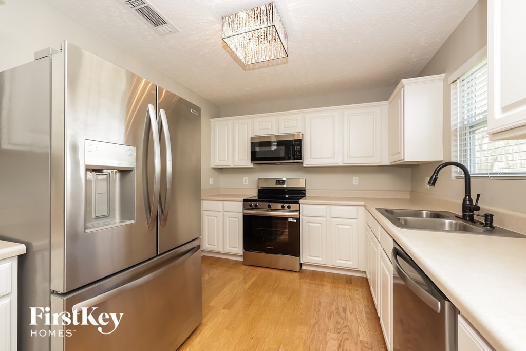 A kitchen with a stainless steel refrigerator and white cabinets.