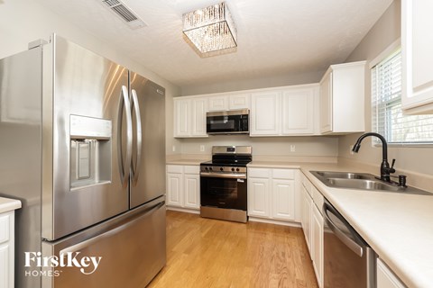 A kitchen with a stainless steel refrigerator and white cabinets.