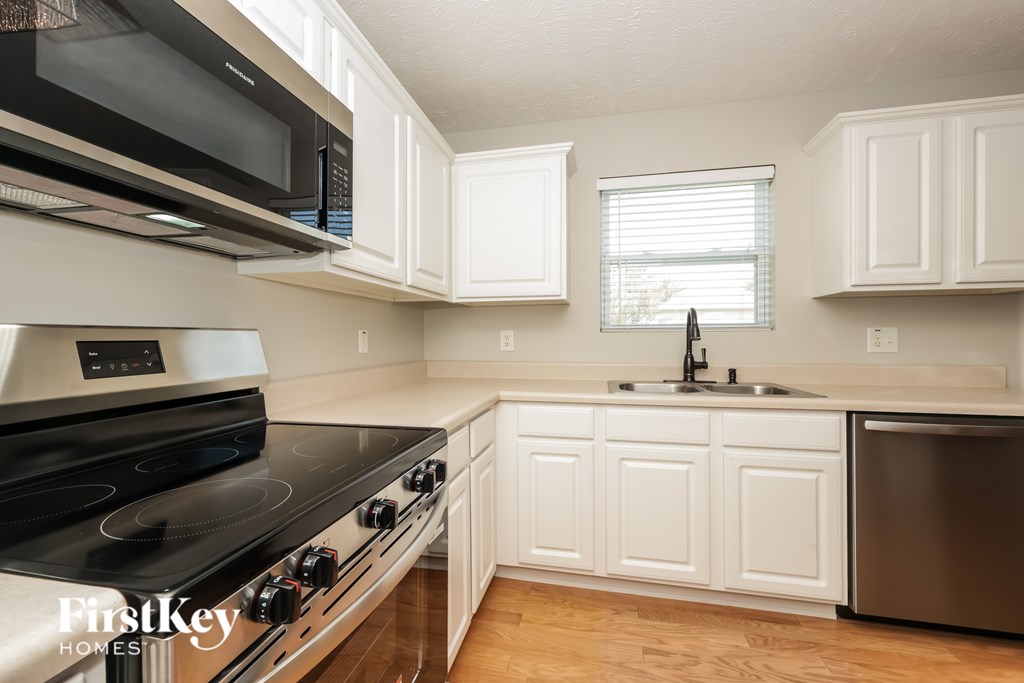 A kitchen with white cabinets and a black stove top oven.