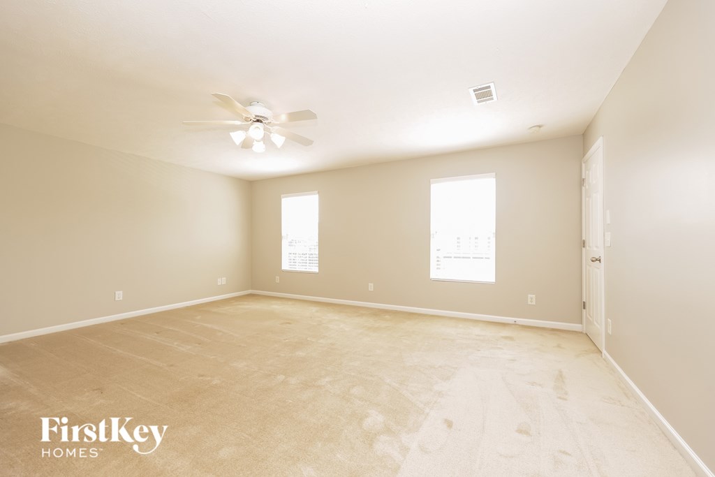 A room with a ceiling fan and two windows.