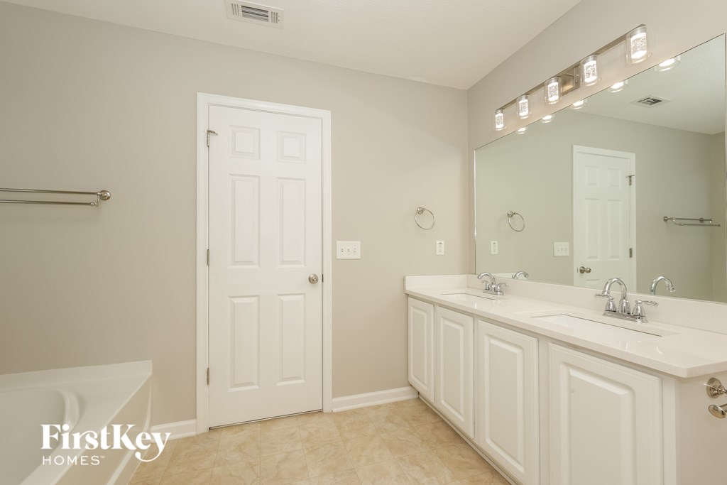 A white bathroom with a mirror and lights above it.