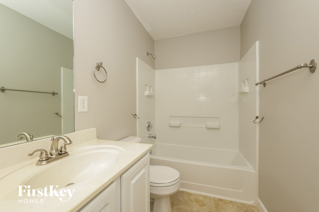 A white bathroom with a toilet, sink, and shower.