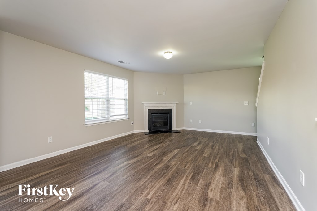 A spacious living room with wood flooring and a fireplace.