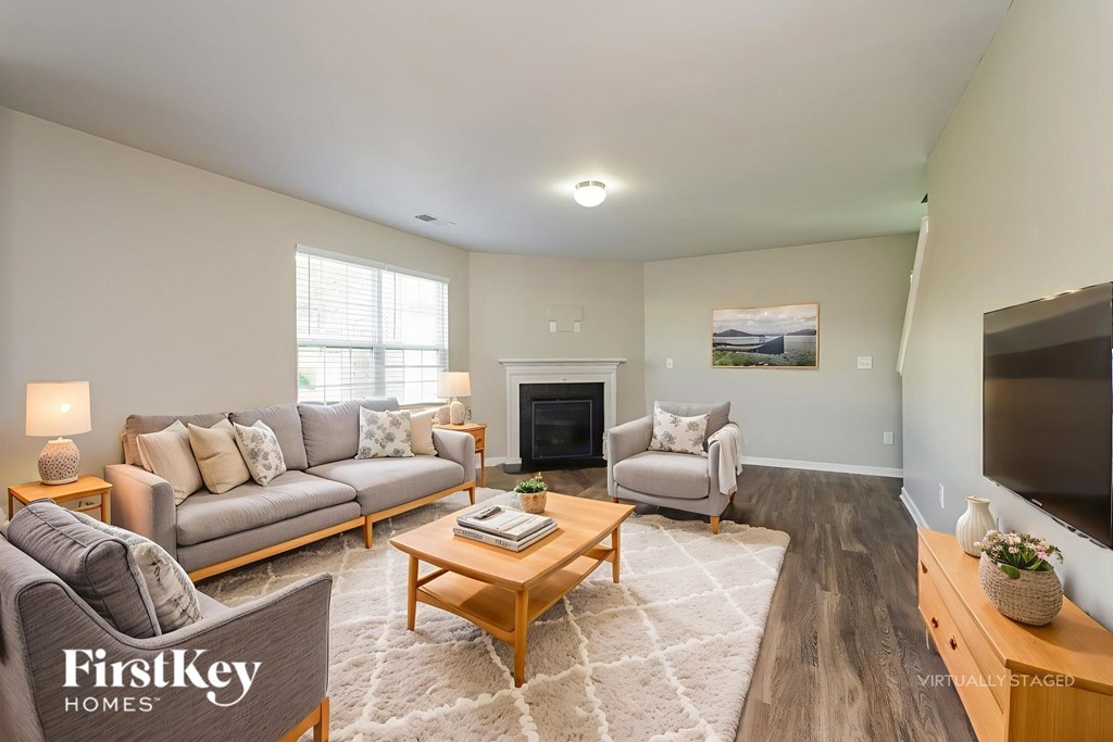 A living room with a grey couch, a wooden coffee table, and a fireplace.