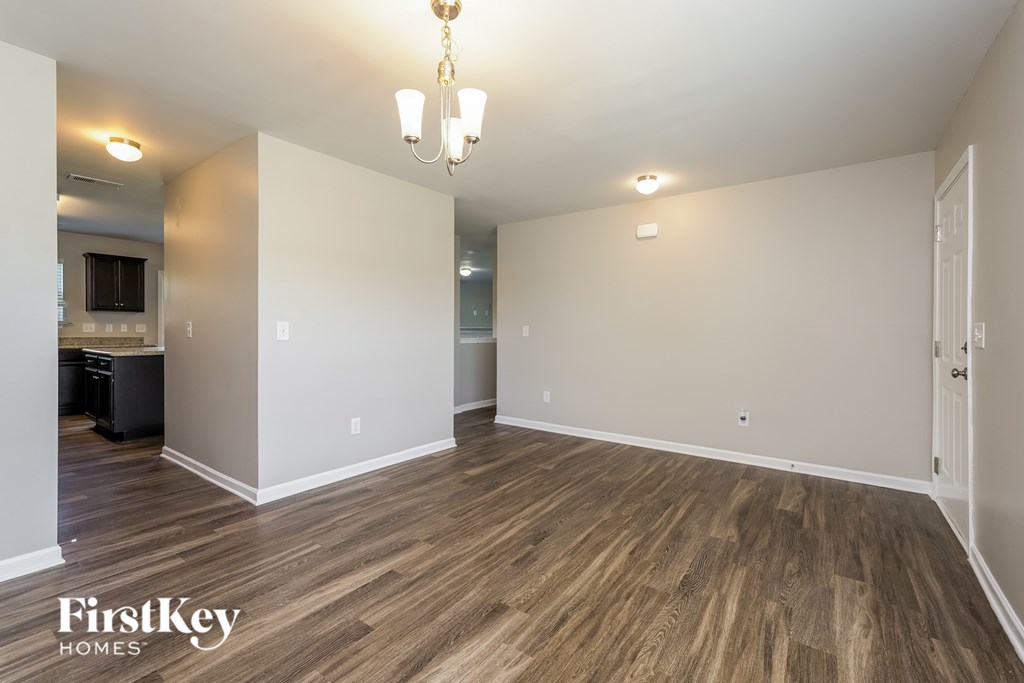 A room with wooden flooring and a chandelier hanging from the ceiling.