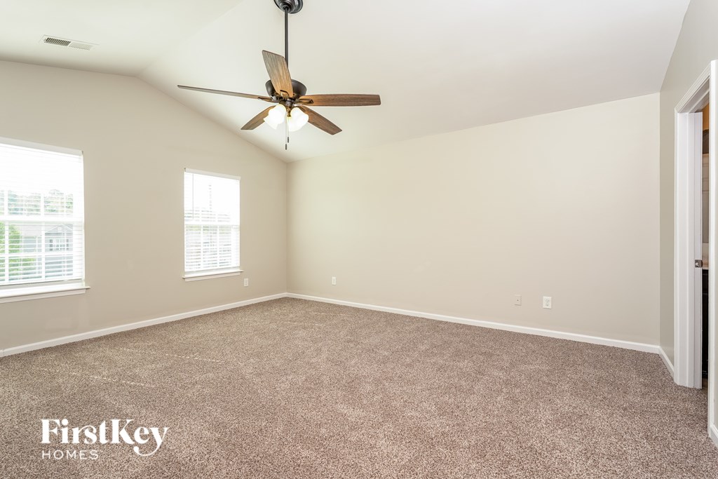 A room with a ceiling fan and two windows.