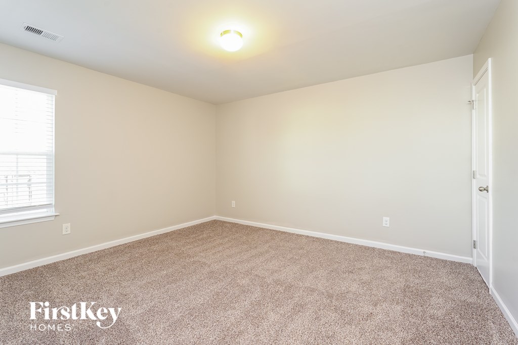 A room with a carpeted floor and a door on the right side.