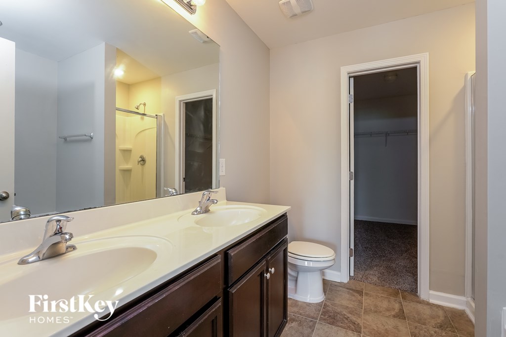 A bathroom with a sink, toilet and mirror.